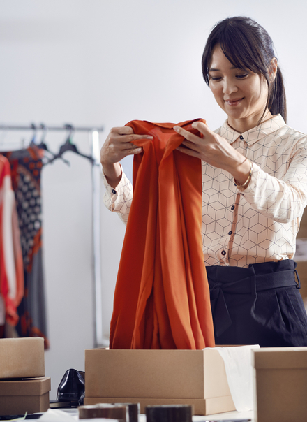 person in a backroom of a store opening a dress
